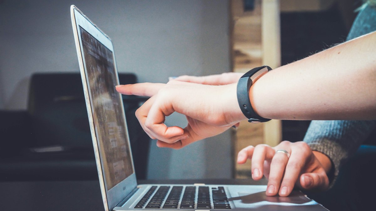 A hand pointing at a laptop screen