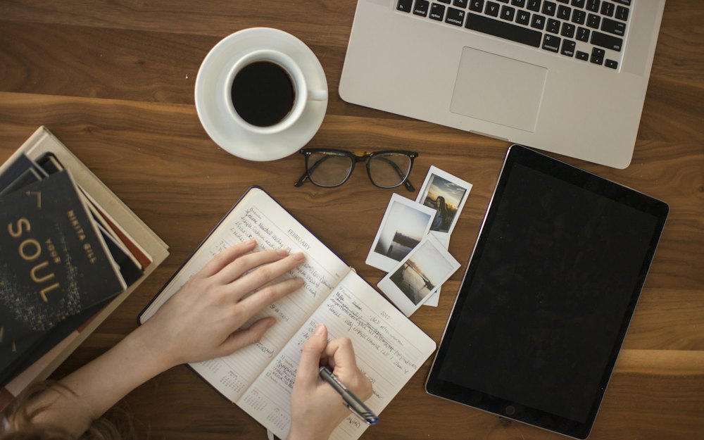 A notebook, tablet and coffee on a desk